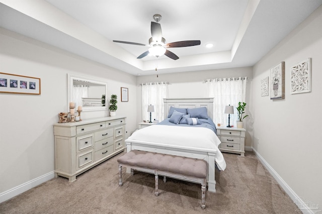 carpeted bedroom with ceiling fan and a raised ceiling