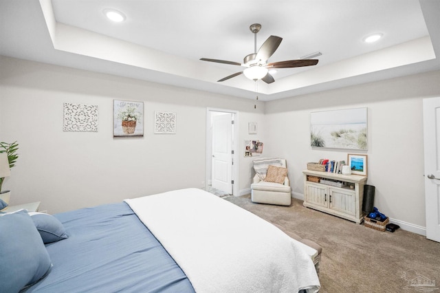 carpeted bedroom featuring a raised ceiling and ceiling fan