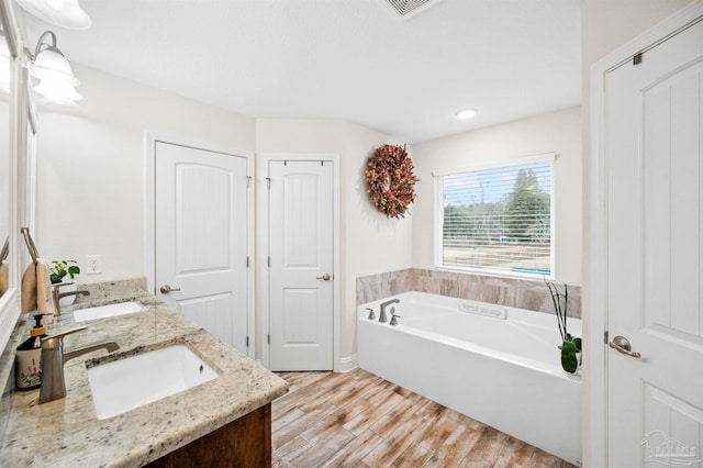 bathroom featuring vanity, a tub to relax in, and hardwood / wood-style floors