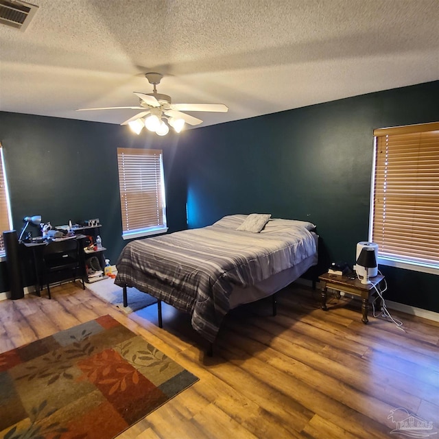 bedroom featuring ceiling fan, a textured ceiling, and hardwood / wood-style flooring