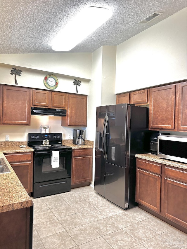1405 College Pkwy, Gulf Breeze, FL 32563 - kitchen featuring light tile patterned flooring, a textured ceiling, under cabinet range hood, visible vents, and black appliances