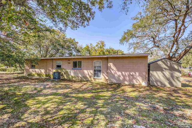 rear view of house featuring concrete block siding and central air condition unit