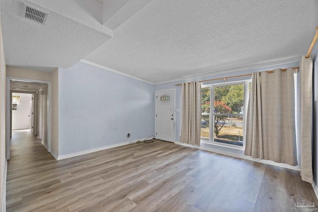 spare room featuring a textured ceiling, wood finished floors, visible vents, and baseboards