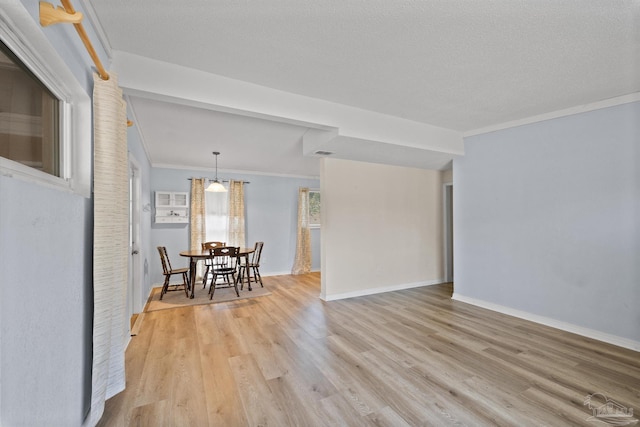 interior space with baseboards, a textured ceiling, light wood-style flooring, and crown molding