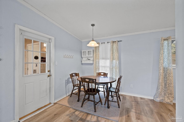 dining space featuring crown molding, wood finished floors, and baseboards