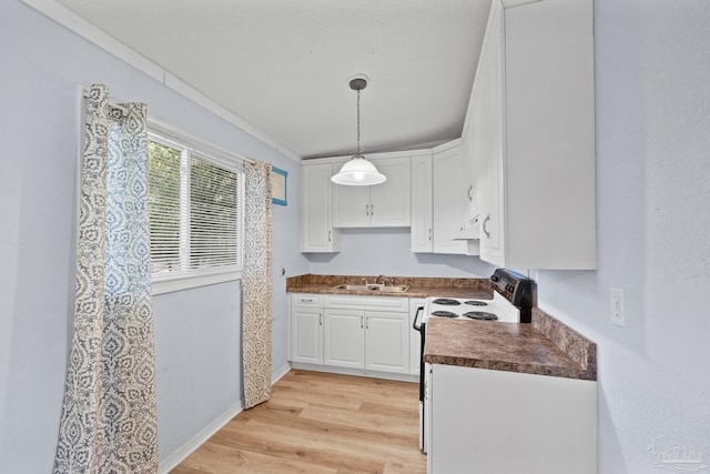 kitchen featuring dark countertops, light wood-type flooring, electric range oven, white cabinetry, and a sink