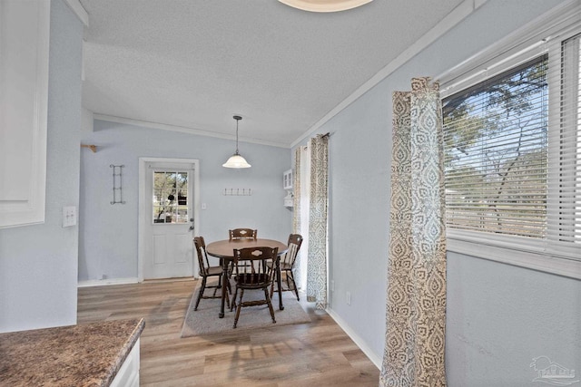 dining area featuring baseboards, a textured ceiling, light wood-style flooring, and crown molding