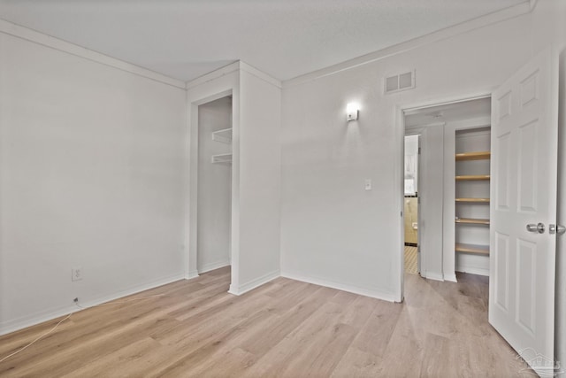 unfurnished room featuring visible vents, light wood-type flooring, baseboards, and ornamental molding