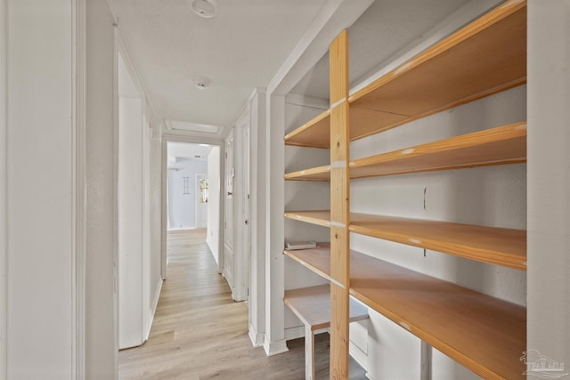 corridor with attic access, baseboards, and wood finished floors