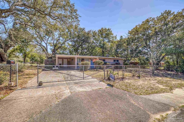 ranch-style home featuring a fenced front yard, driveway, and a gate