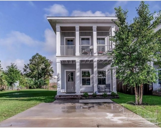 neoclassical home featuring a porch, a balcony, and a front lawn