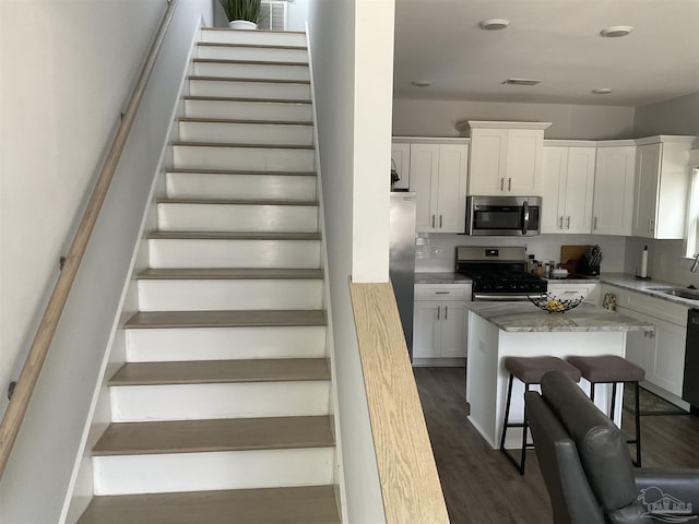 staircase featuring visible vents and wood finished floors
