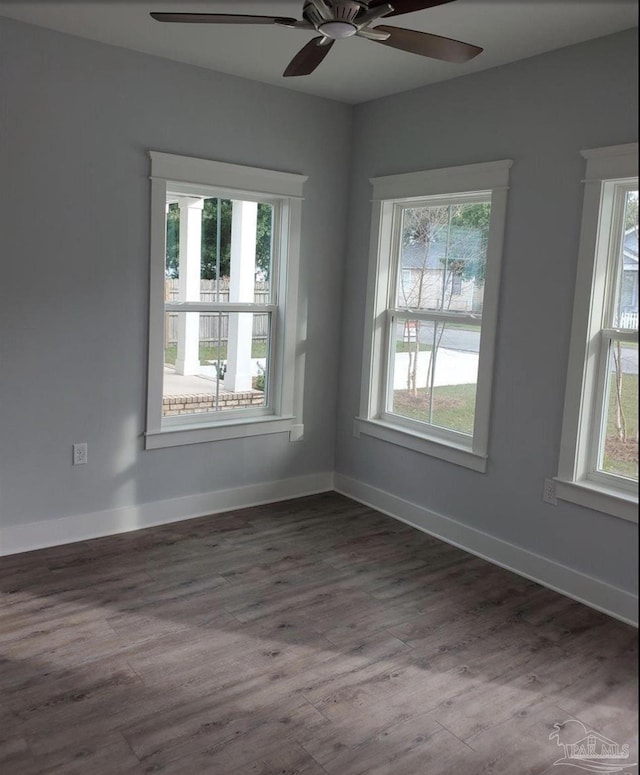 empty room featuring plenty of natural light, a ceiling fan, and dark wood-style flooring