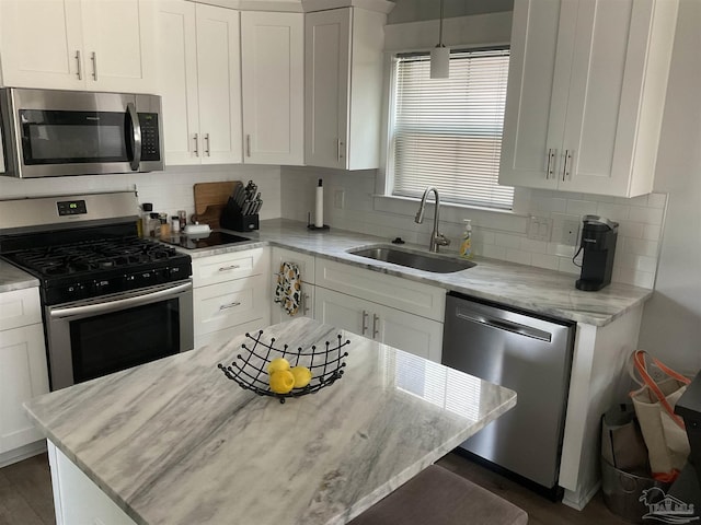kitchen featuring a sink, light stone counters, stainless steel appliances, and white cabinetry