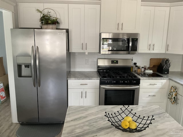 kitchen with white cabinetry, appliances with stainless steel finishes, wood finished floors, and tasteful backsplash