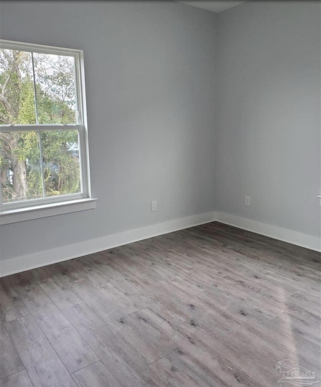 spare room featuring baseboards and wood finished floors