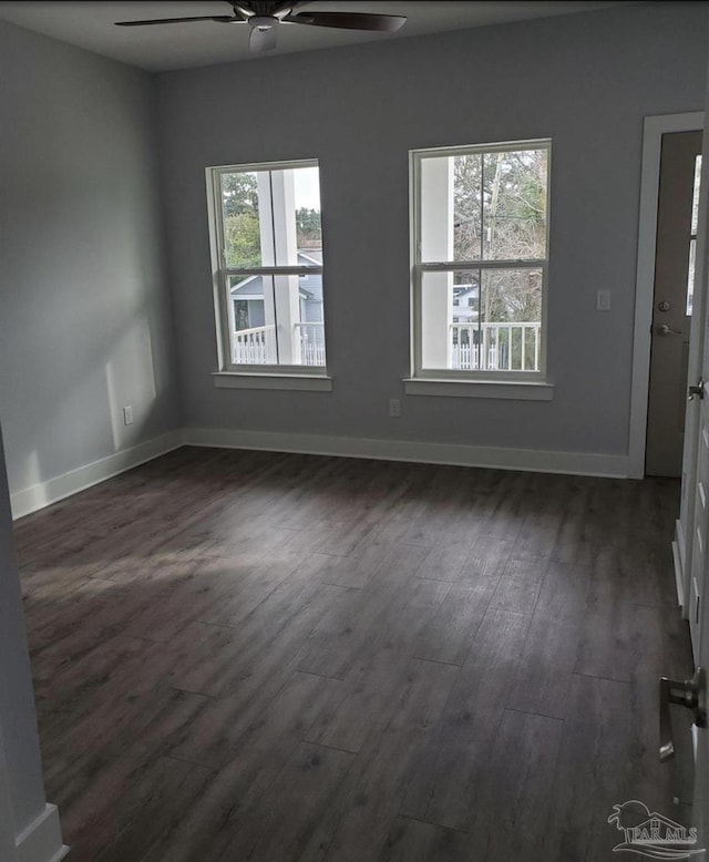 spare room featuring a ceiling fan, baseboards, and dark wood finished floors
