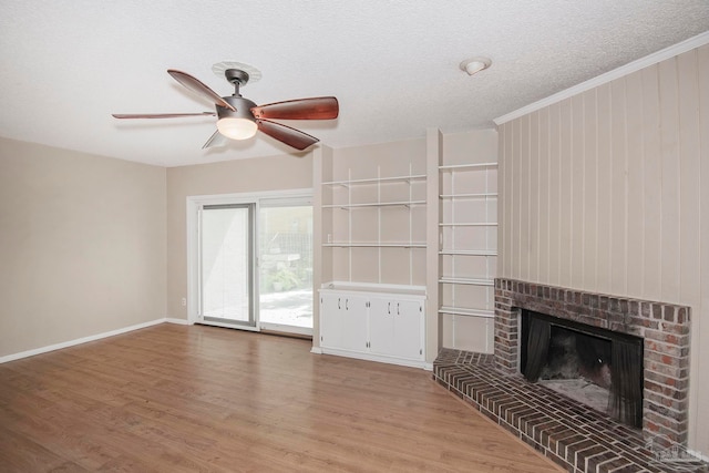 unfurnished living room featuring light wood-type flooring, a textured ceiling, ceiling fan, a fireplace, and ornamental molding