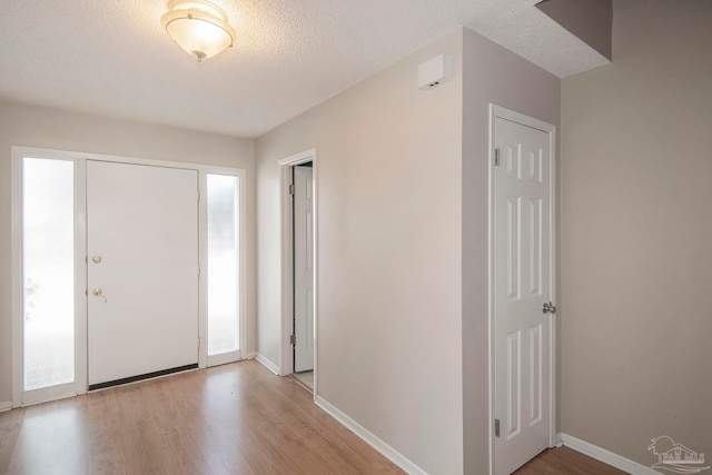 foyer entrance with light hardwood / wood-style flooring and a textured ceiling