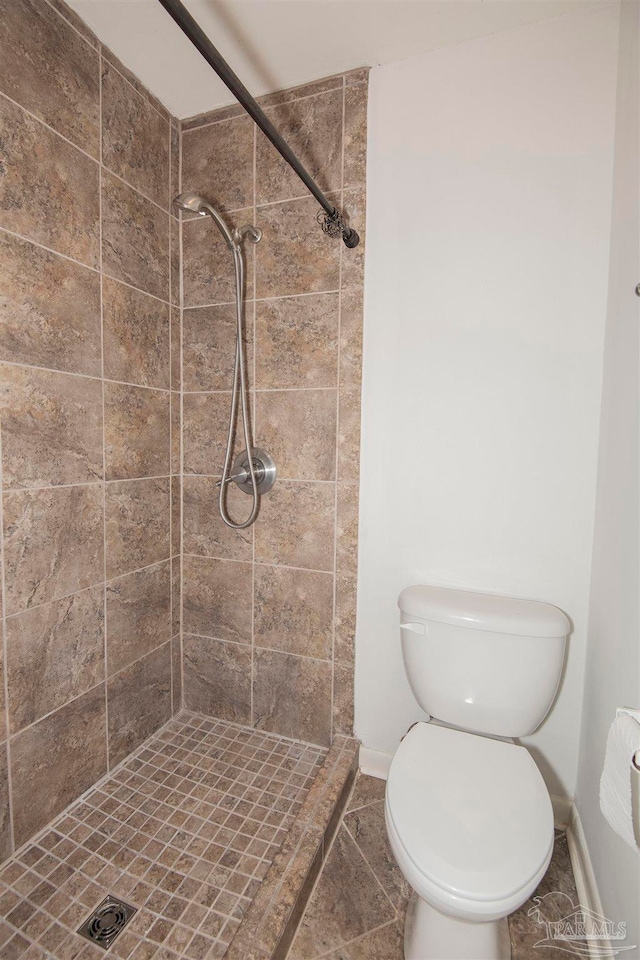 bathroom with tile patterned floors, a tile shower, and toilet