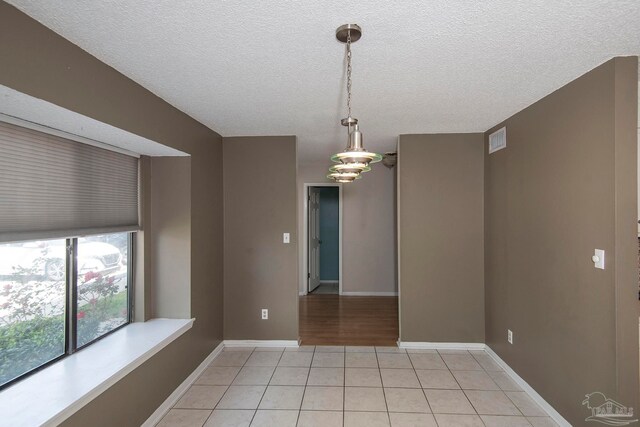 spare room with an inviting chandelier, tile patterned floors, and a textured ceiling