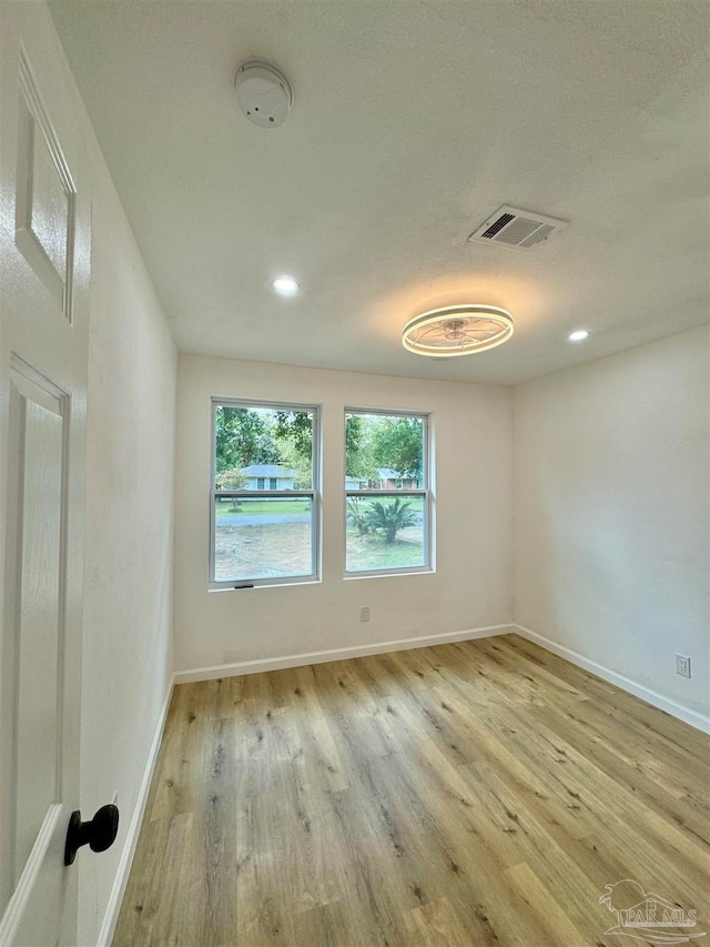 unfurnished room with a textured ceiling and light hardwood / wood-style floors