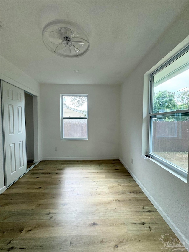 unfurnished bedroom featuring multiple windows and light hardwood / wood-style flooring