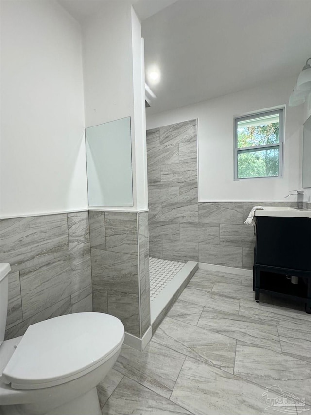 bathroom with vanity, toilet, tile walls, and walk in shower