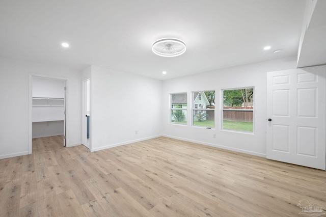 unfurnished bedroom featuring a walk in closet, a closet, and light hardwood / wood-style flooring