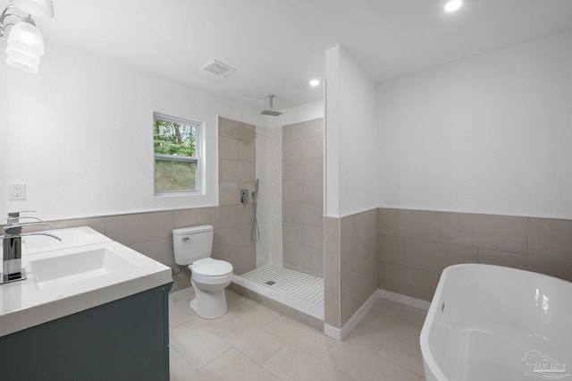 full bathroom with separate shower and tub, tile patterned floors, toilet, tile walls, and vanity