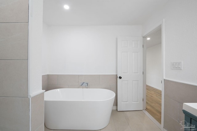 bathroom with tile patterned flooring, vanity, a bathtub, and tile walls