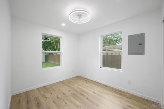 unfurnished room with electric panel and light hardwood / wood-style floors