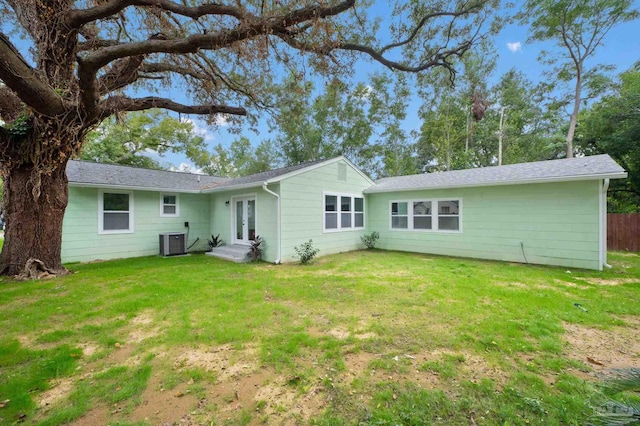 rear view of property featuring cooling unit and a yard