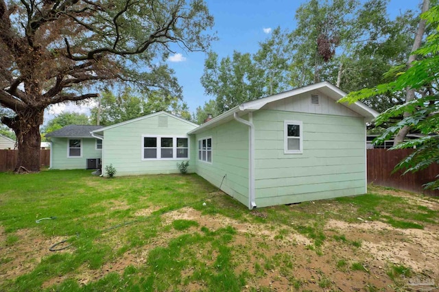 rear view of house featuring a lawn and central air condition unit