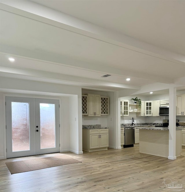 kitchen featuring stone counters, cream cabinetry, light hardwood / wood-style flooring, appliances with stainless steel finishes, and beam ceiling