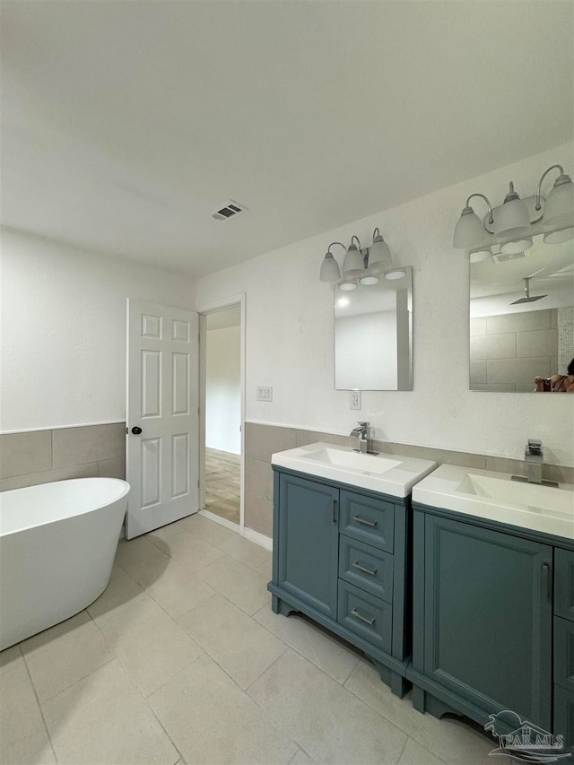 bathroom featuring tile patterned floors, tile walls, a bathtub, and vanity