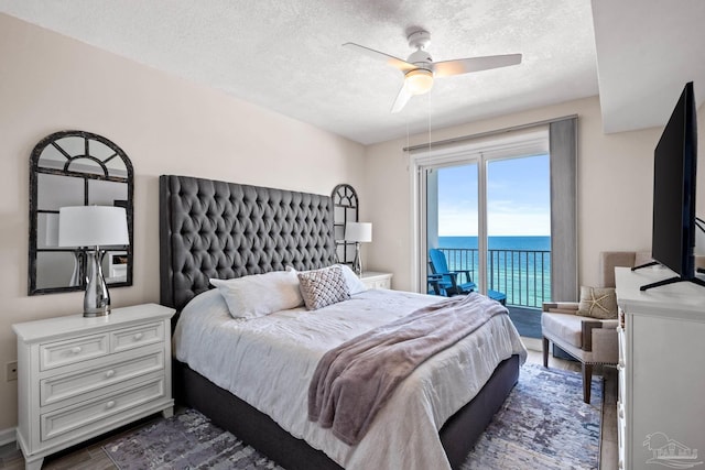 bedroom featuring ceiling fan, access to exterior, dark hardwood / wood-style flooring, and a textured ceiling