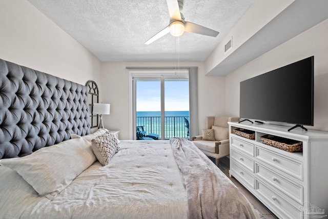 bedroom with ceiling fan, access to exterior, and a textured ceiling