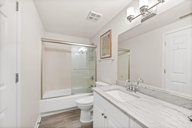 full bathroom with wood-type flooring, combined bath / shower with glass door, vanity, and toilet