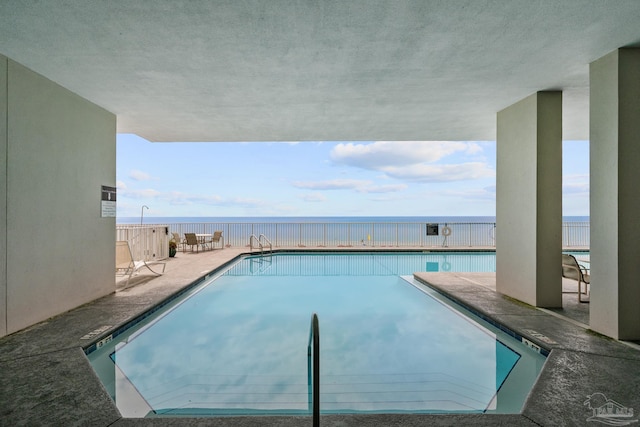 view of pool featuring a water view and a patio