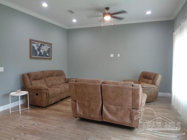 living room featuring ornamental molding, light wood-type flooring, and ceiling fan