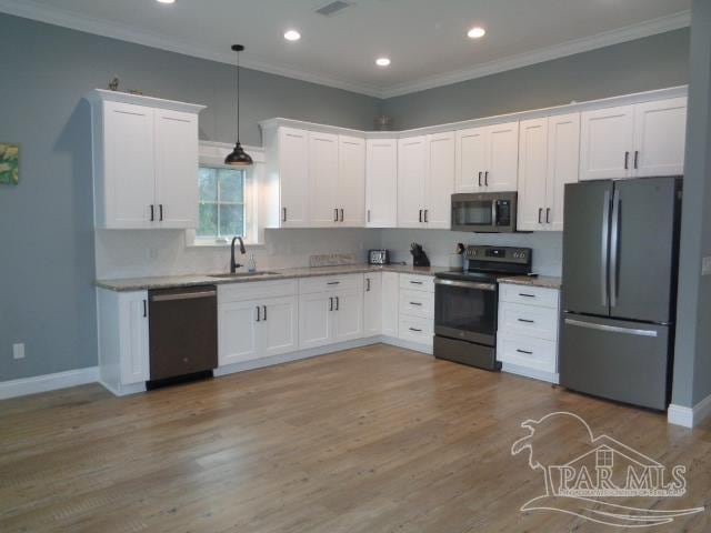 kitchen featuring stainless steel appliances, sink, pendant lighting, white cabinetry, and light hardwood / wood-style floors