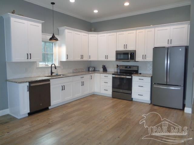 kitchen featuring white cabinetry, appliances with stainless steel finishes, sink, and decorative light fixtures