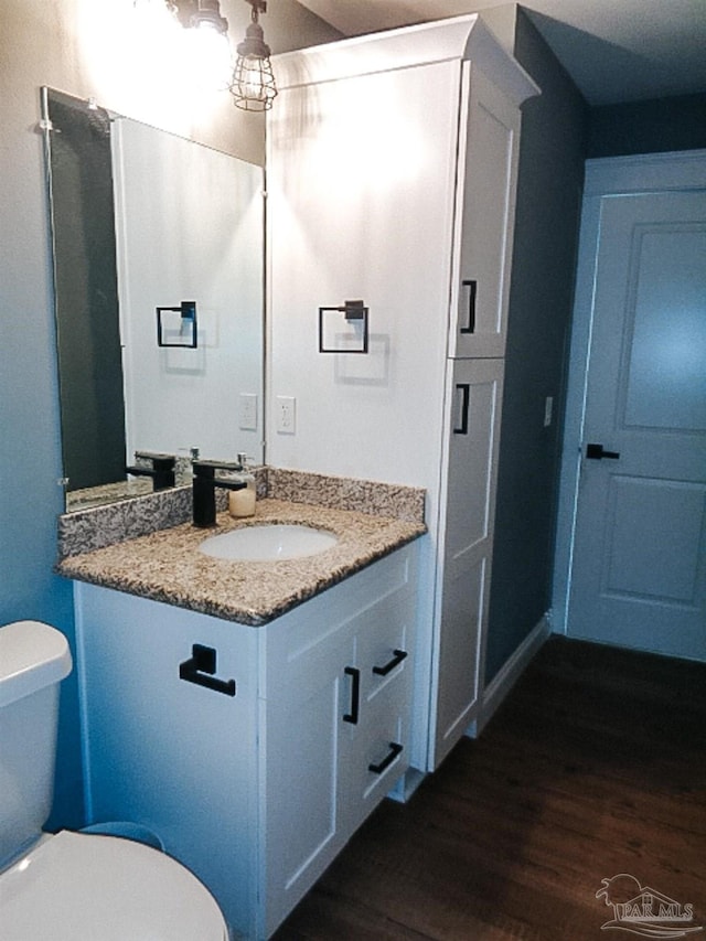 bathroom with toilet, hardwood / wood-style floors, and vanity