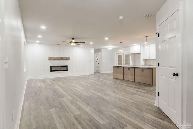 unfurnished living room with ceiling fan and light hardwood / wood-style flooring