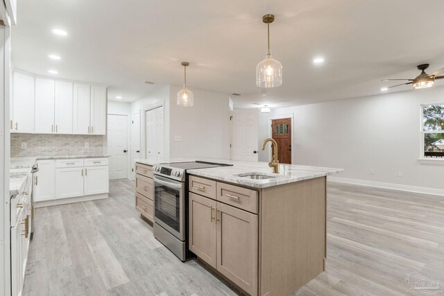 kitchen featuring white cabinets, hanging light fixtures, an island with sink, stainless steel range with electric stovetop, and sink