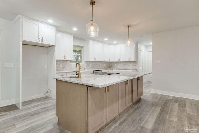 kitchen featuring a kitchen island, decorative light fixtures, white cabinetry, and light stone counters