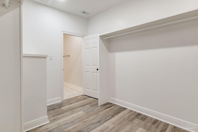 walk in closet with light hardwood / wood-style flooring