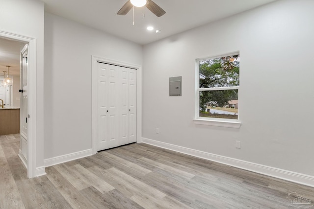 unfurnished bedroom featuring a closet, ceiling fan, light hardwood / wood-style floors, and electric panel