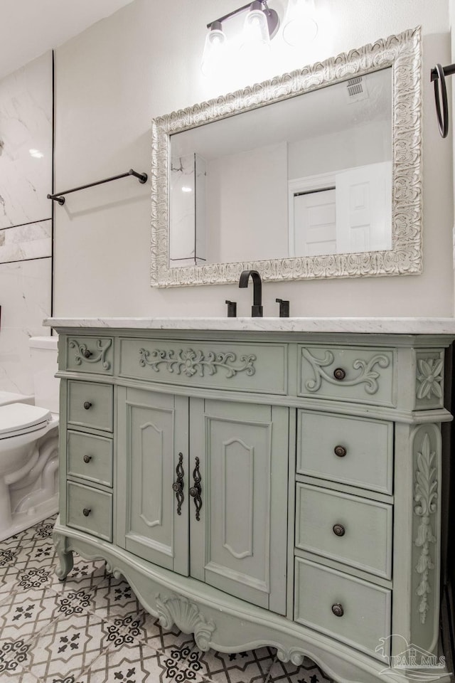 bathroom with toilet, vanity, and tile patterned floors